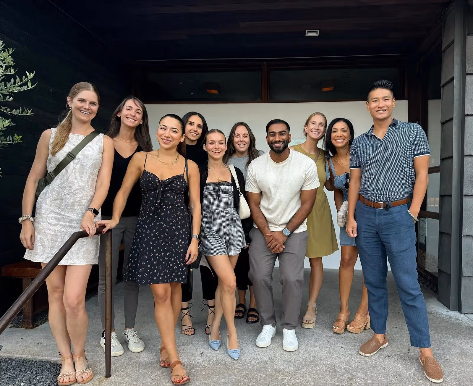 Smiling team members posing together outside an office entrance.